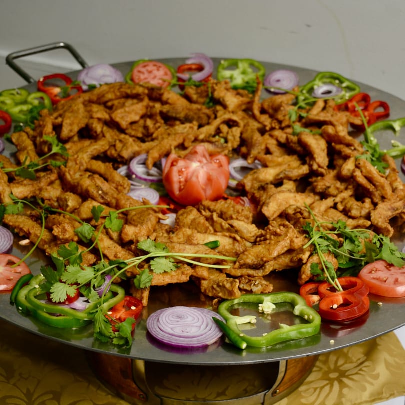 Himalayan Curry House's fried chicken with bell peppers, onions, tomatoes, and cilantro on a large platter.
