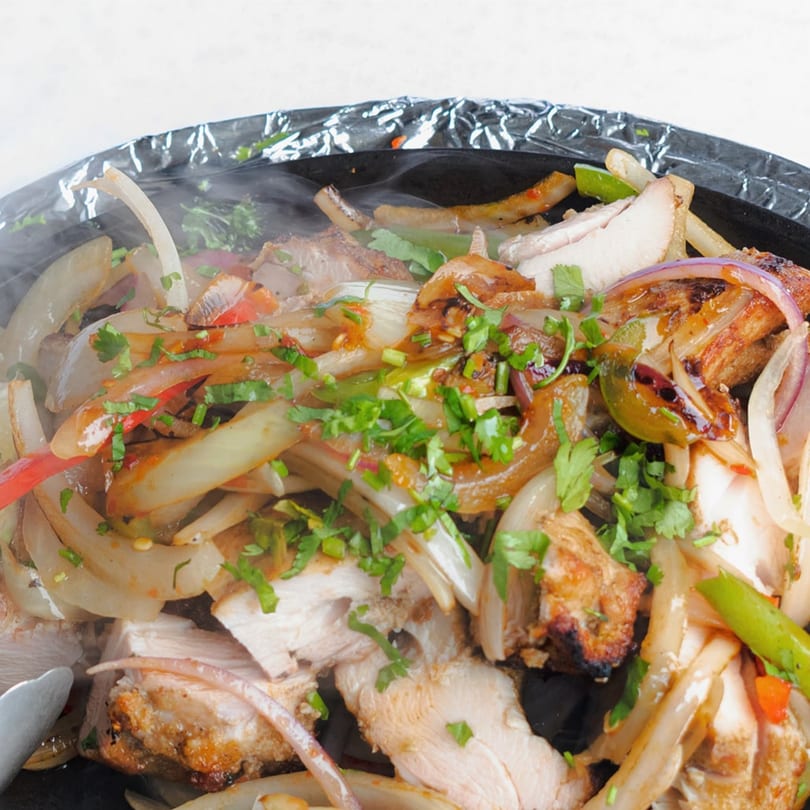 Sizzling chicken fajitas with onions, peppers, and cilantro, served hot at Himalayan Curry House.
